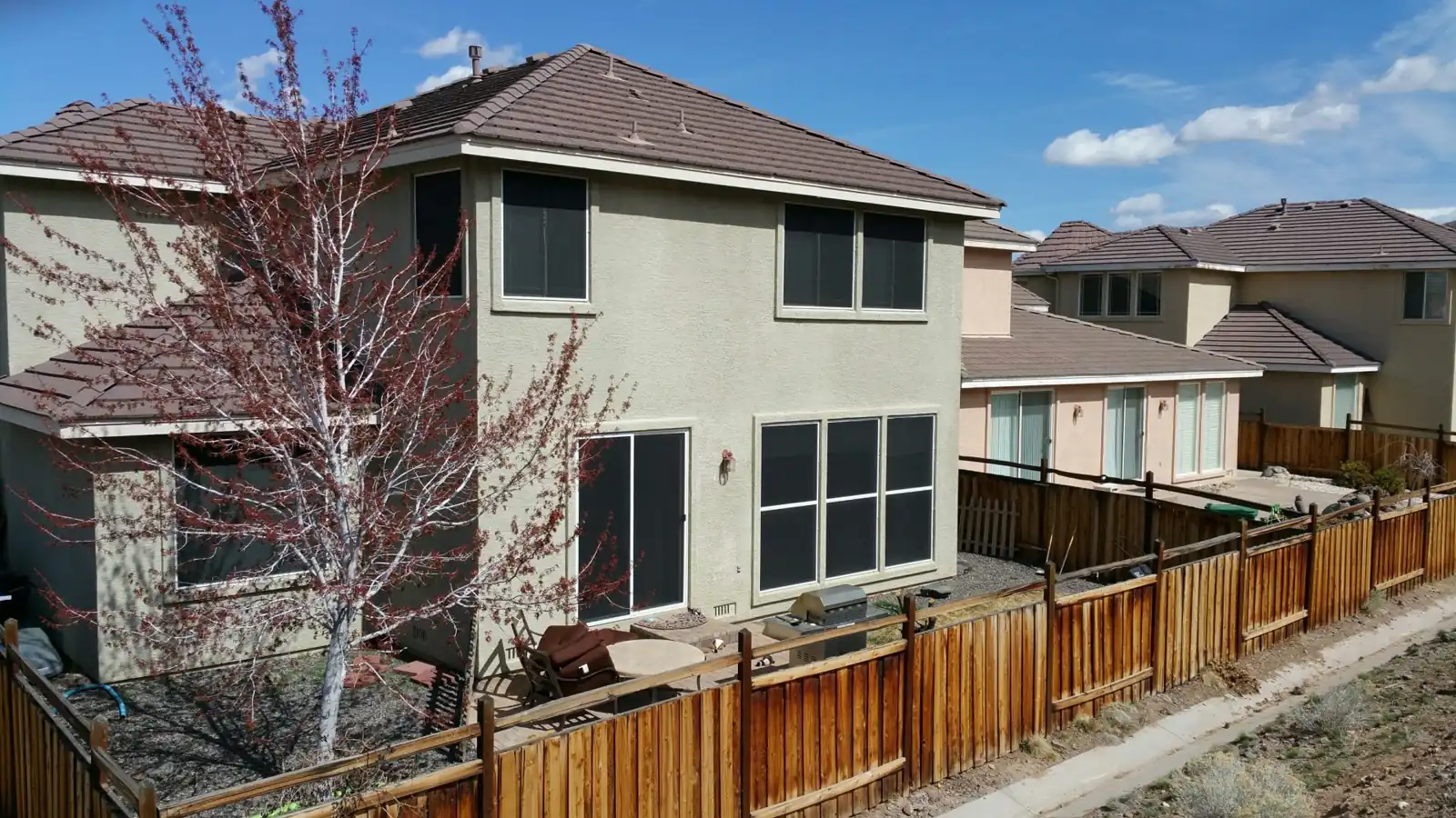 Solar screens installed on the back windows of a two-story home